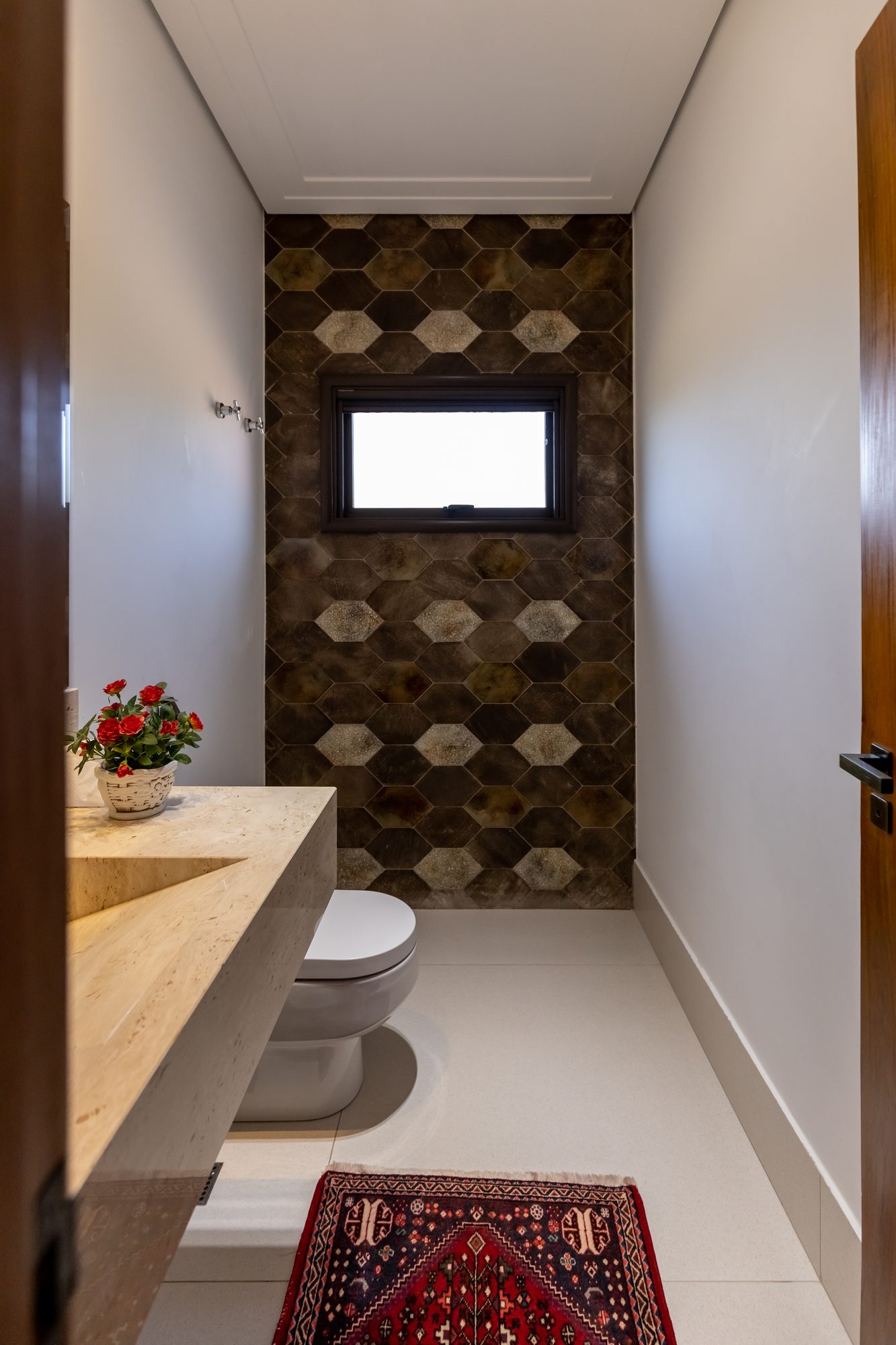 Outro ângulo do lavabo com parede hexagonal e tapete persa