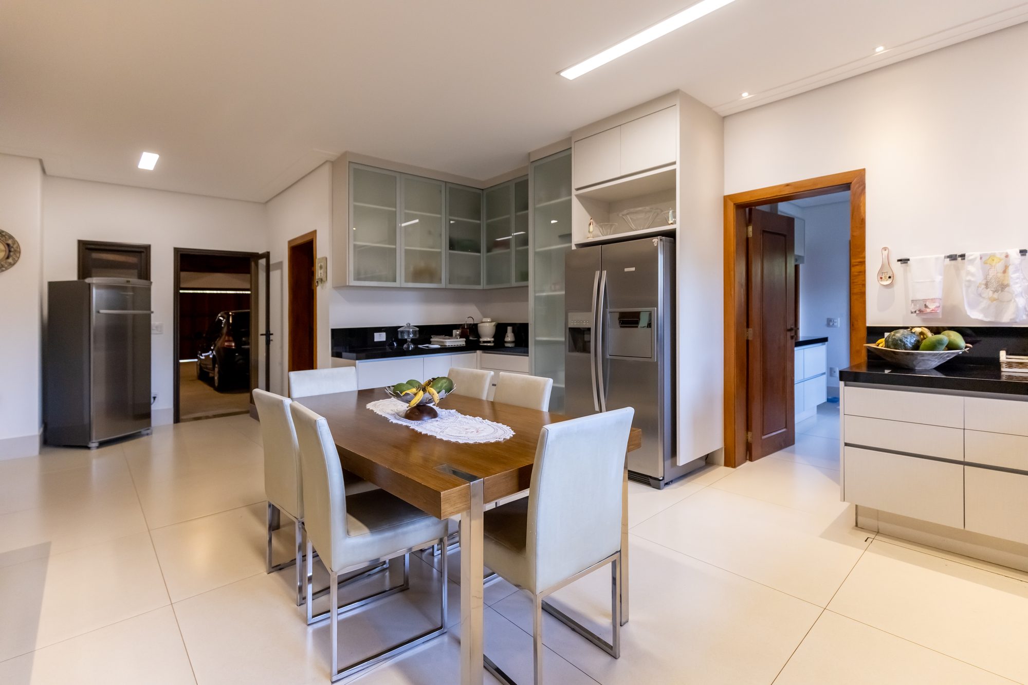 Cozinha vista da copa, com geladeiras e acesso à garagem