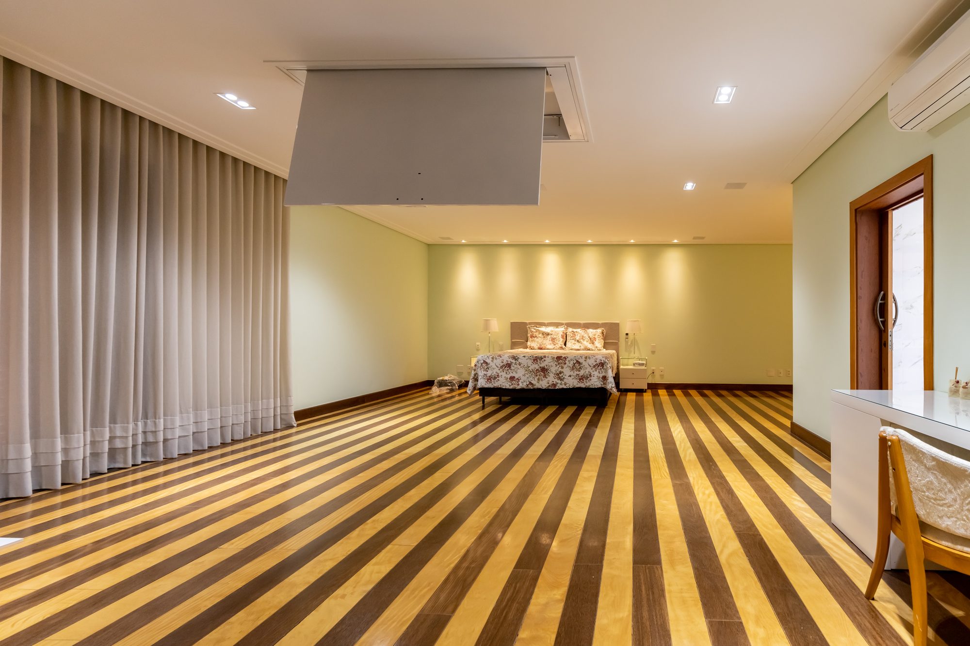 Suíte espaçosa com cama de casal, iluminação suave e cortinas amplas