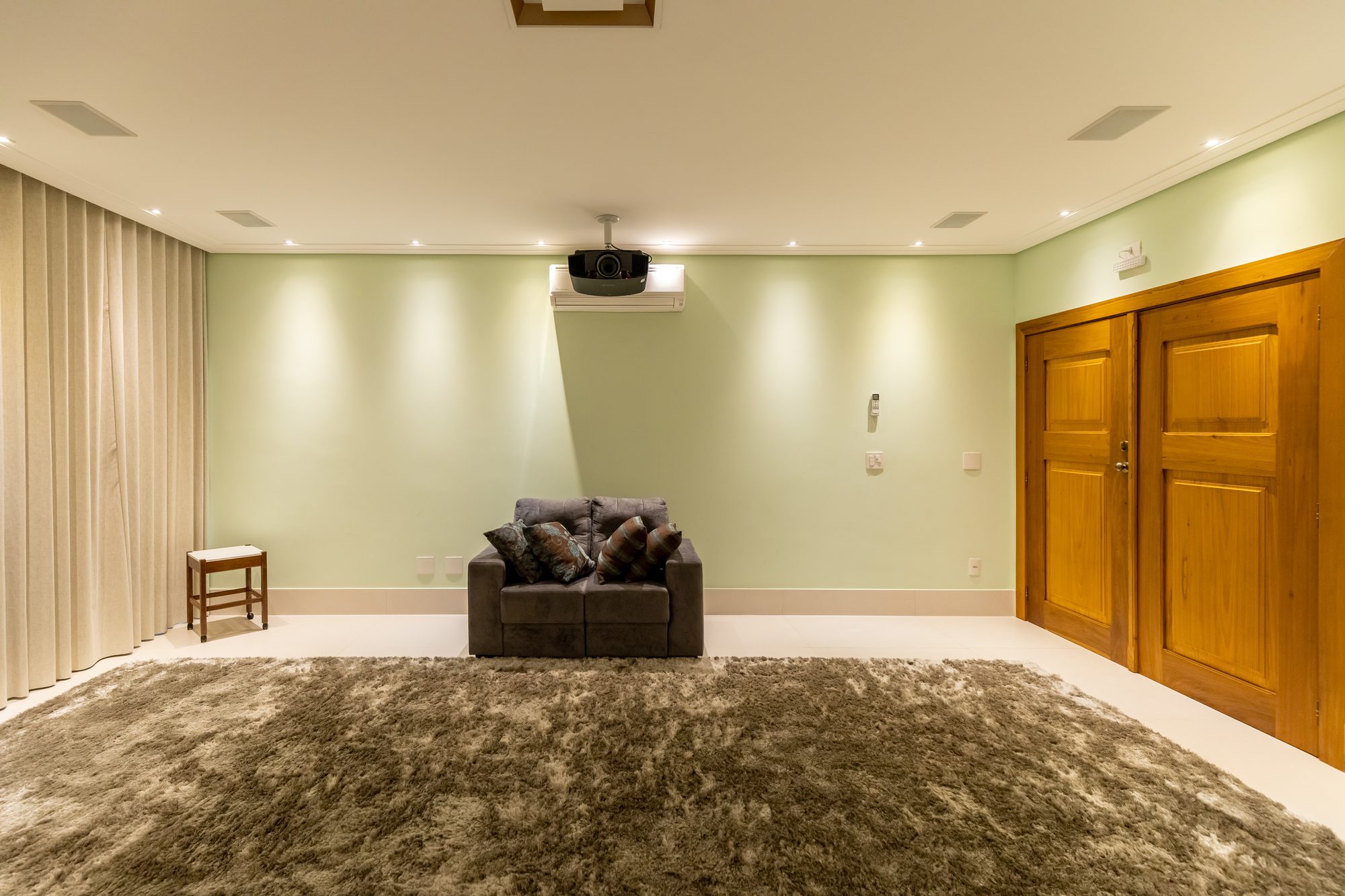 Sala de cinema com poltrona, tapete felpudo e portas de madeira