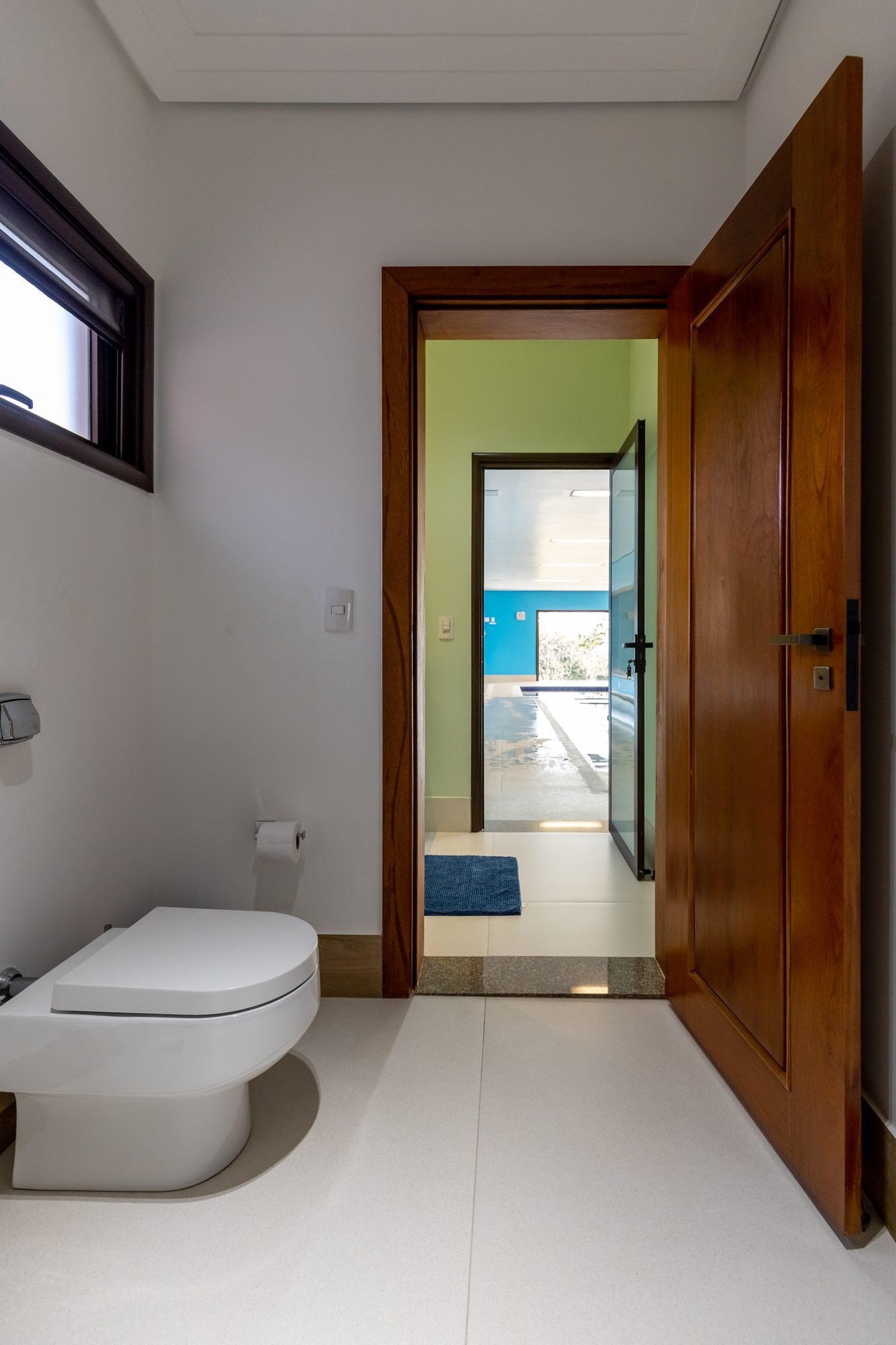Outro banheiro de apoio com porta de madeira e vista para a piscina