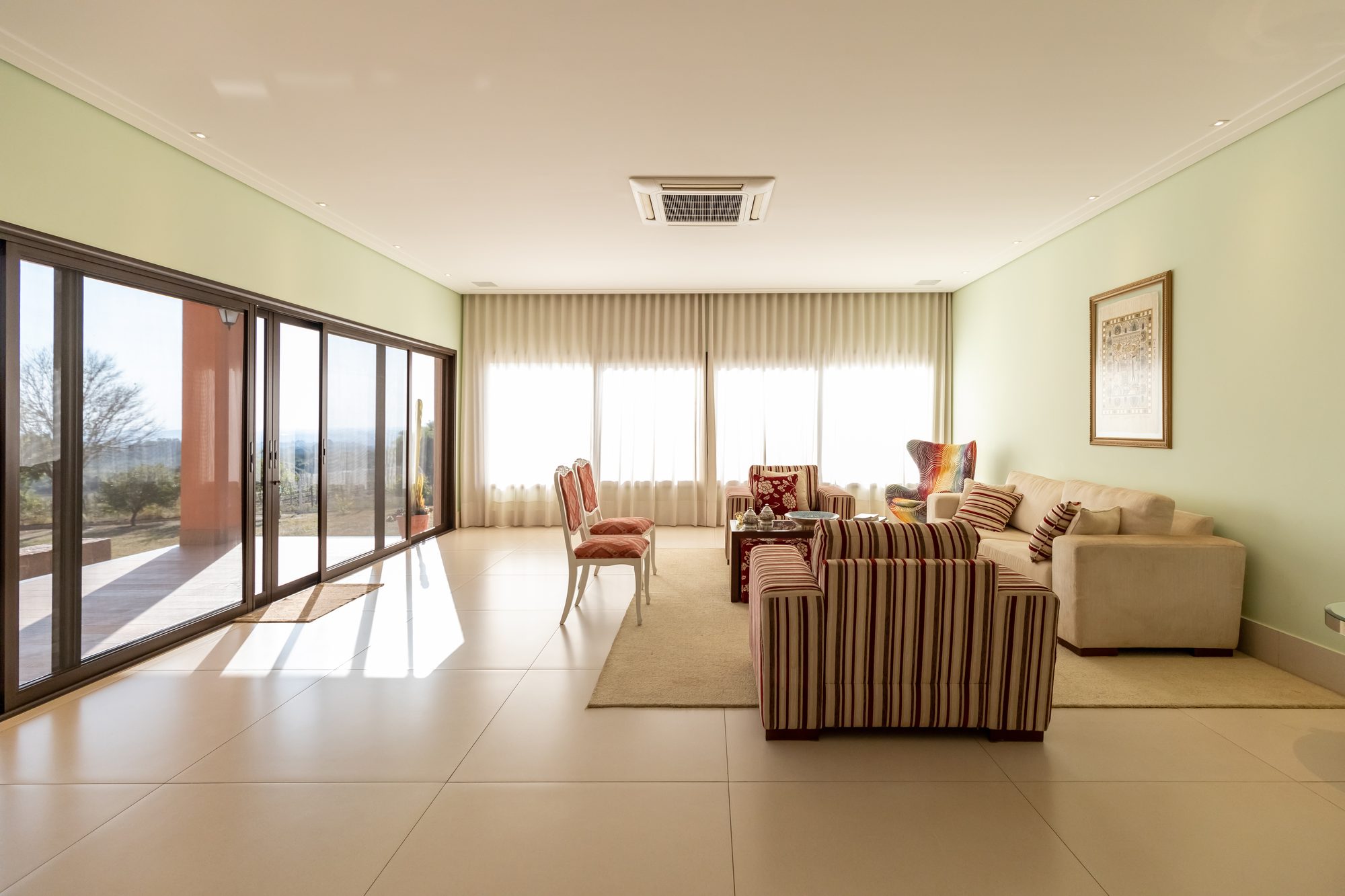 Sala de estar com sofás, janelões e vista para o jardim