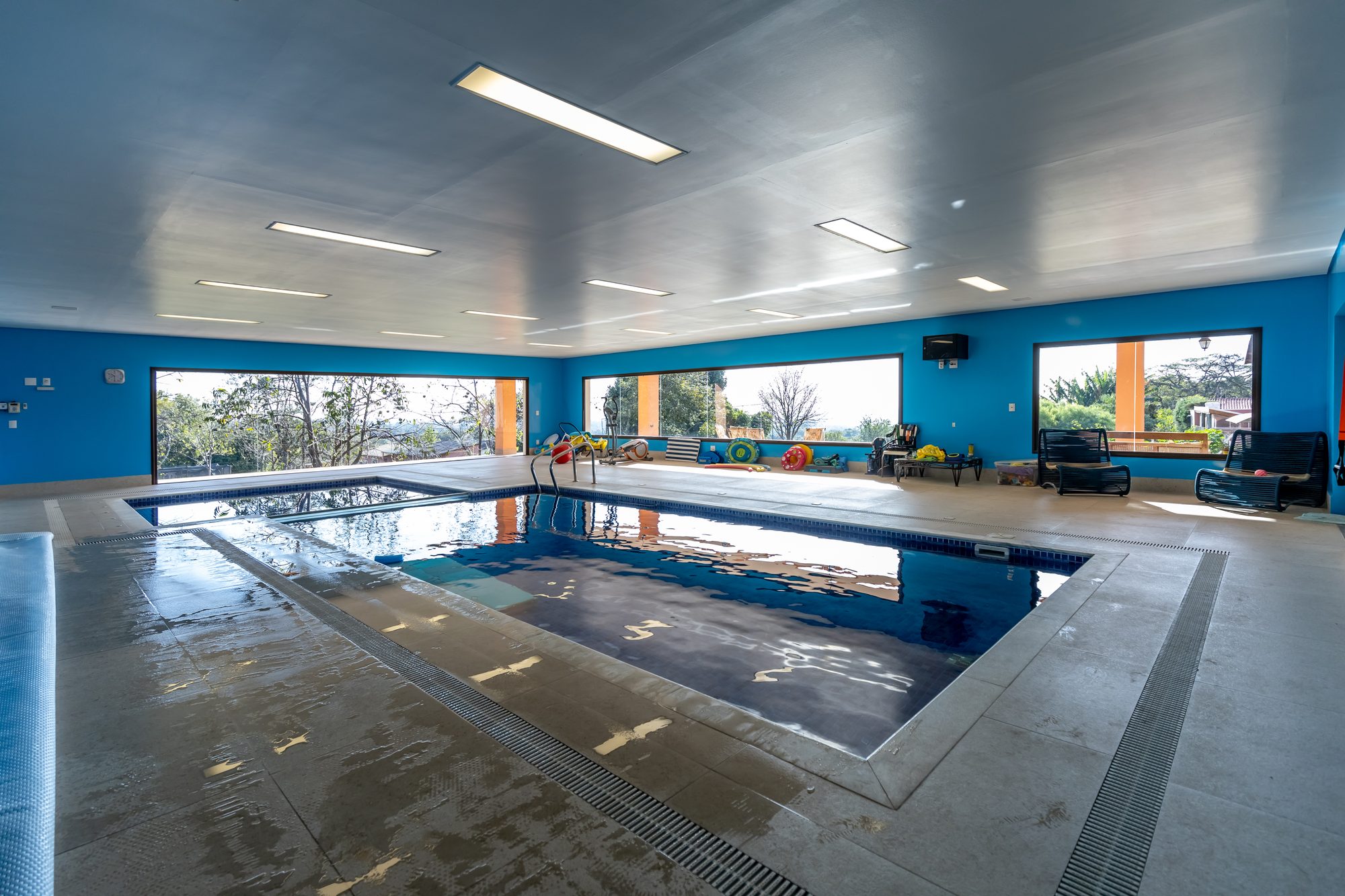 Espaço da piscina interna com poltronas e vista para o horizonte