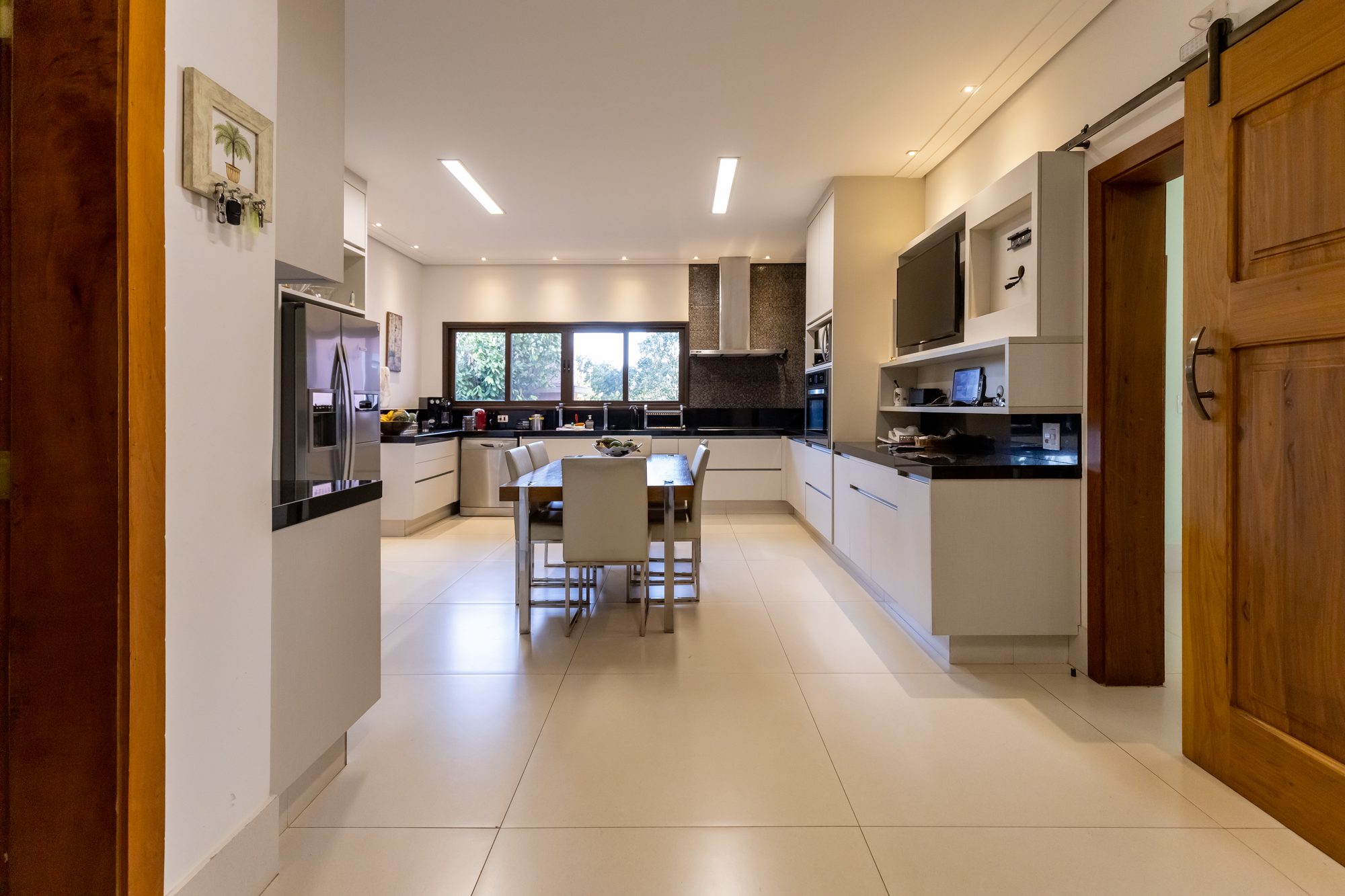 Cozinha ampla com ilha, mesa e eletrodomésticos de inox