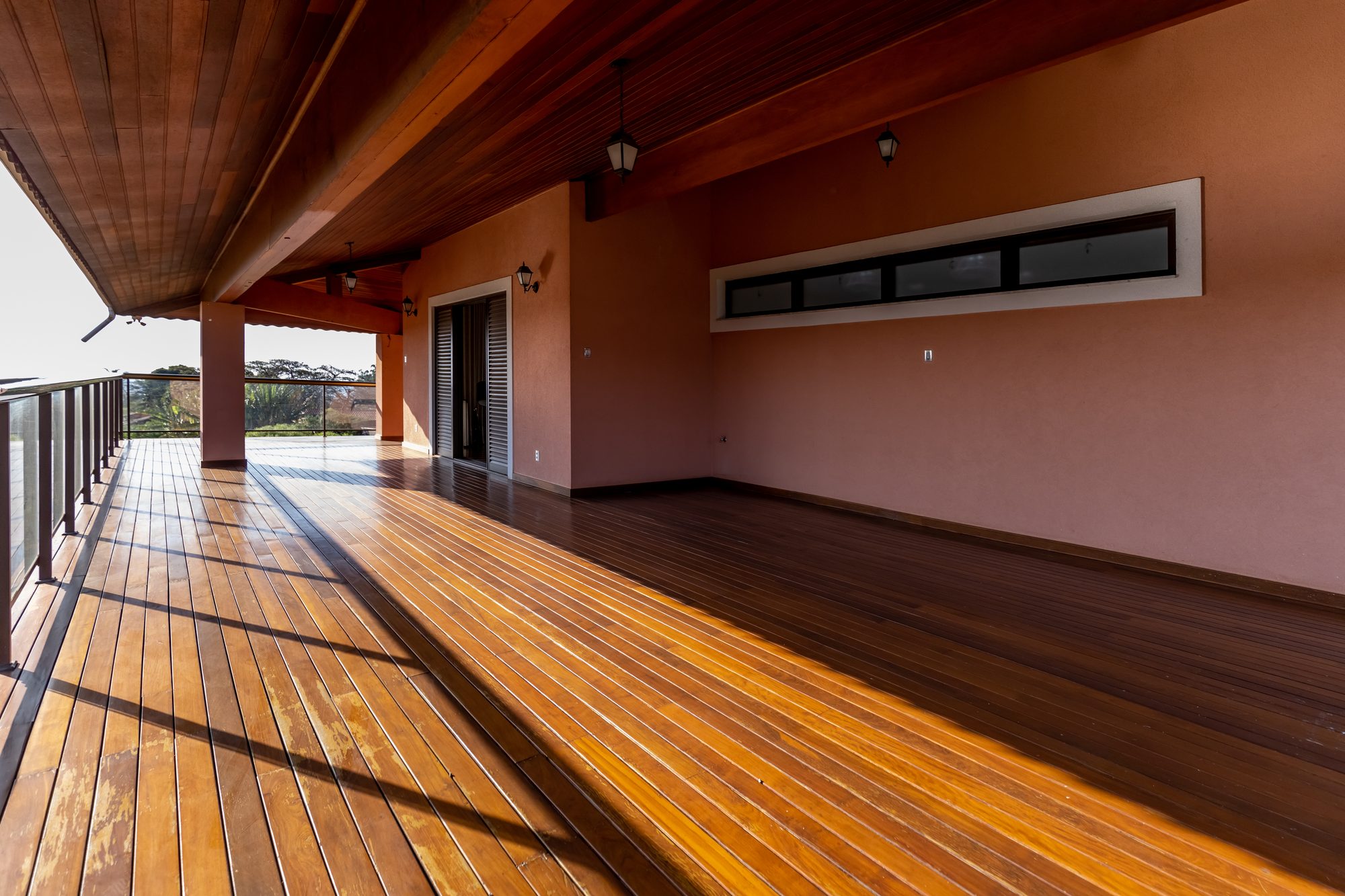 Varanda extensa com lanternas e piso de madeira envernizado