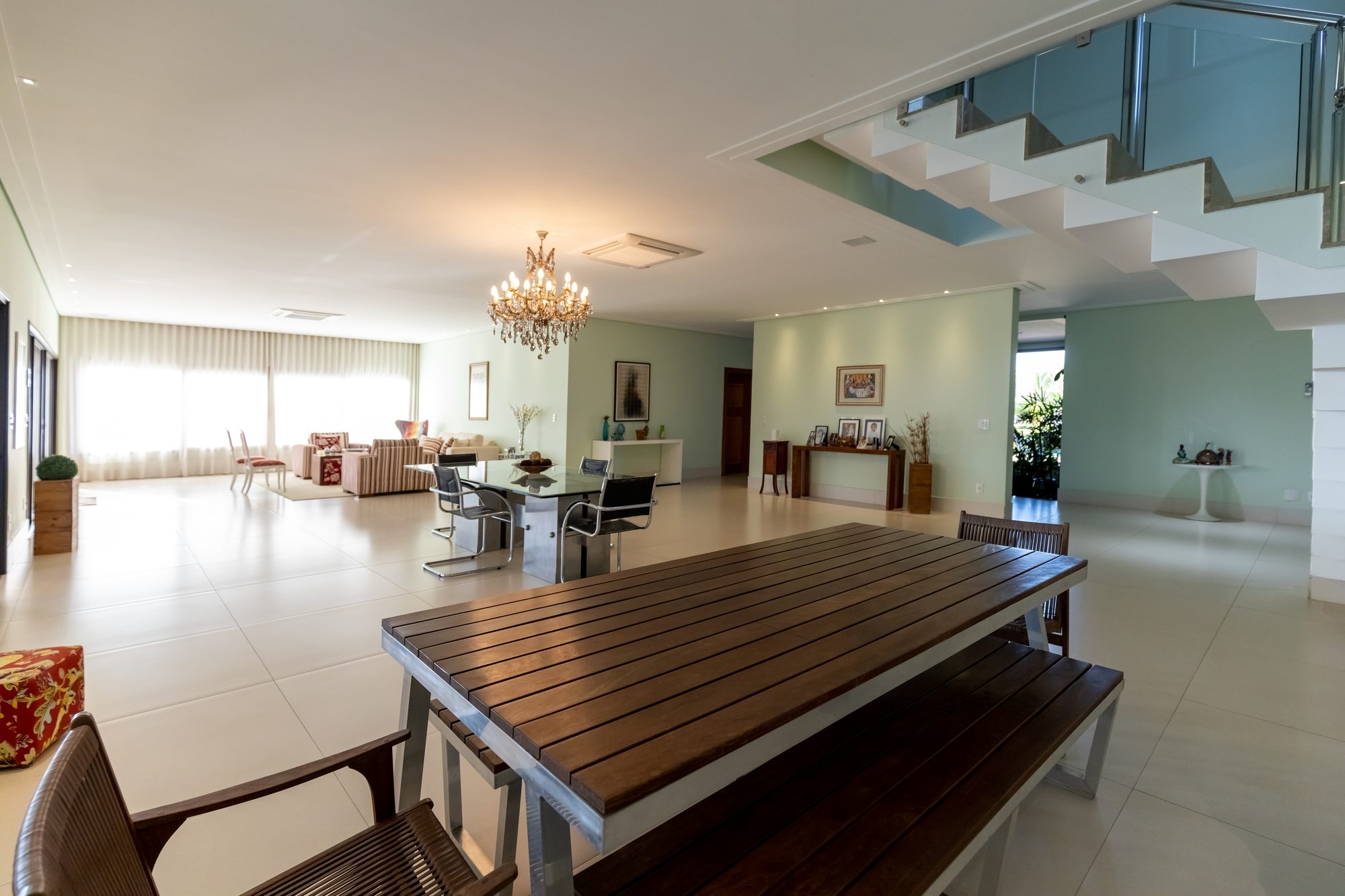 Sala de estar e jantar integradas com mesa de madeira e lustre